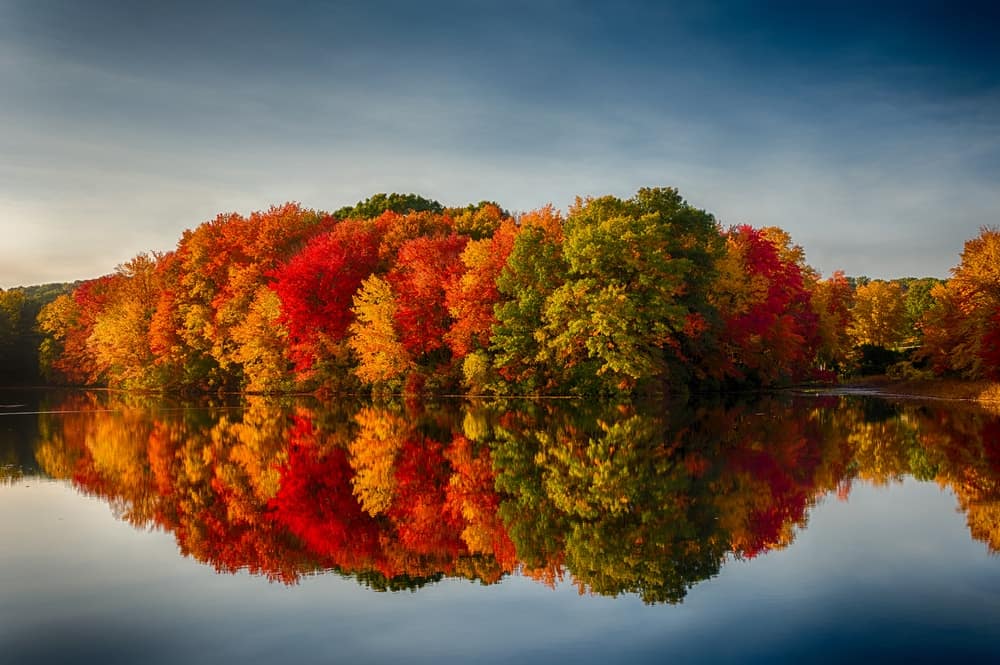 Spacious skies campgrounds showcasing autumn trees reflected in a lake.