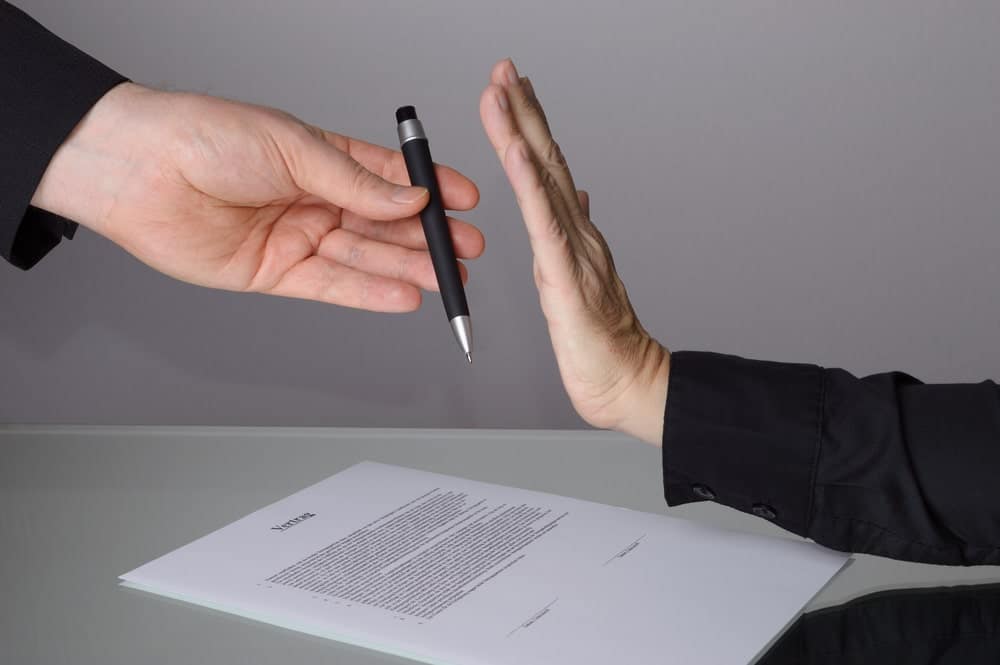 A businessman handing a pen to another person at the Bedwas Glamping Site, signaling an expansion.