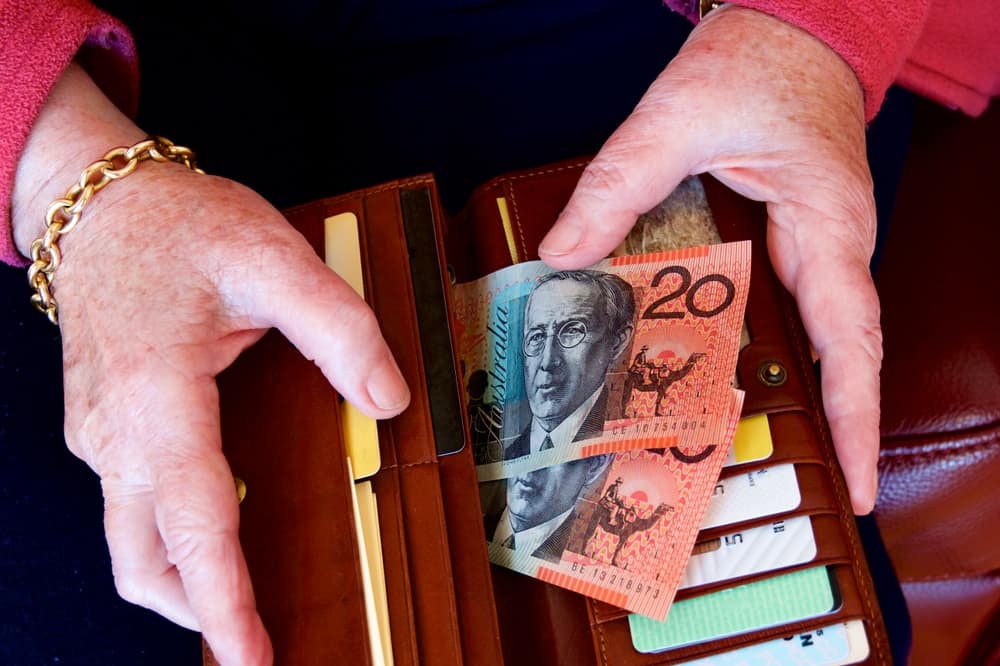 A woman is holding a wallet full of money while traveling.