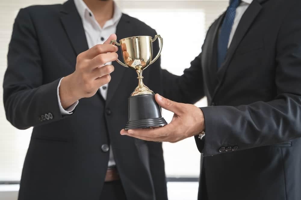 Two businessmen holding a COHCE Award trophy in front of each other.
