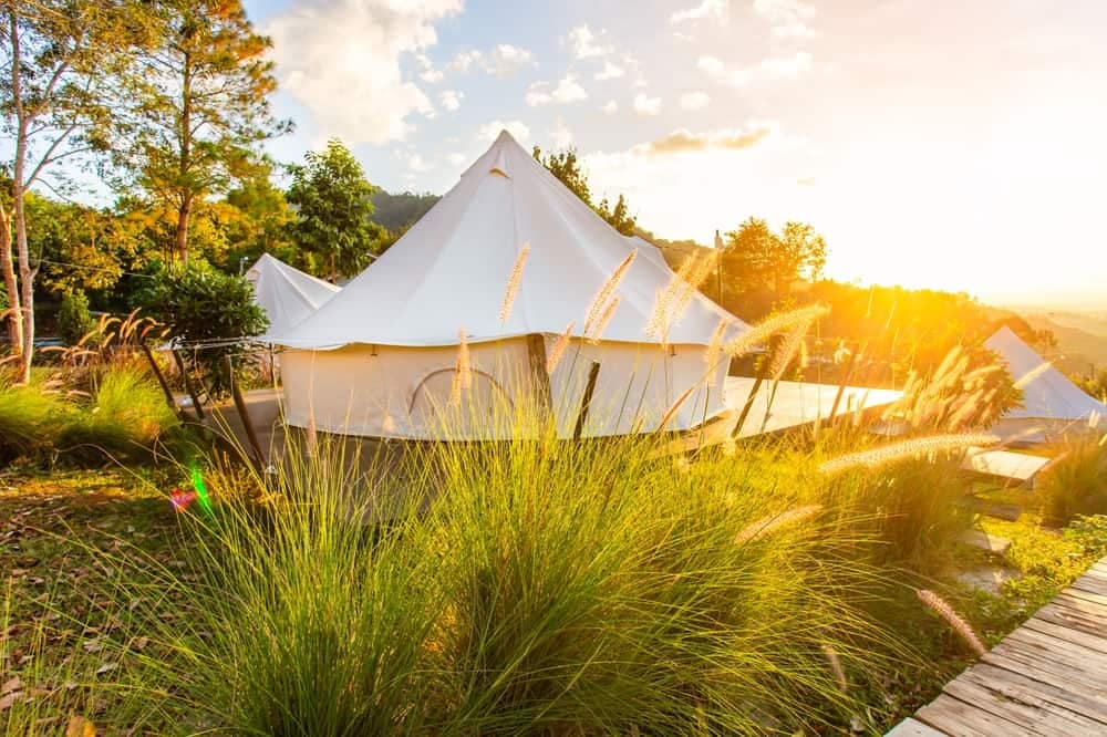 A white tent sits on a wooden deck at sunset, creating the perfect ambiance for a relaxing camping experience in Europe.