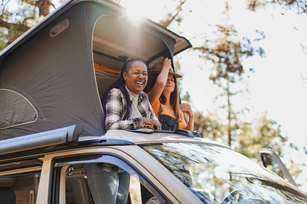 Two people enjoying camping season in the top of a camper van during Memorial Day Weekend.