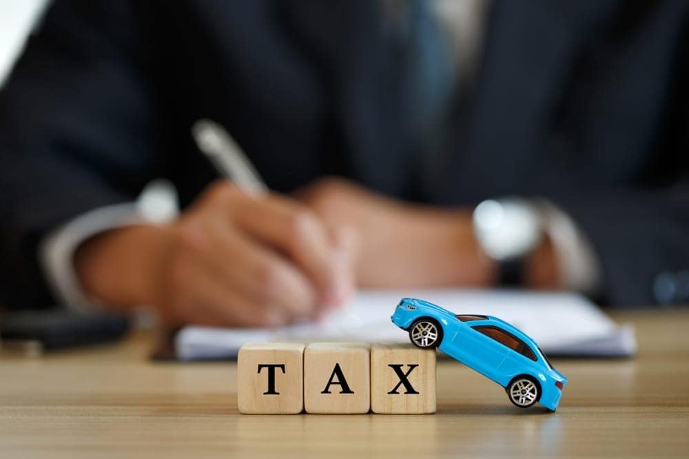 A blue toy car sits on top of a wooden block with the word tax, representing fair tax treatment.