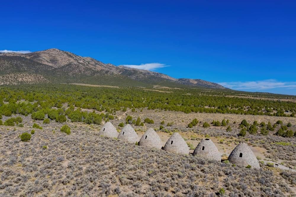 A group of stone huts in the middle of a field, offering free admission for visitors to explore the historic site.