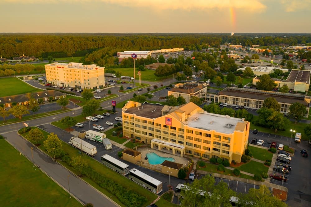 An aerial view of a hotel with a rainbow in the sky, showcasing the vibrant colors and natural beauty that captivate visitors and entice them to explore Robeson County.