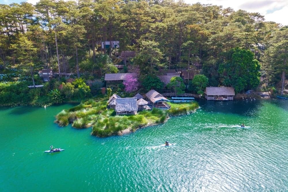 An aerial view of Tuyen Lam Lake with houses on it, a UNESCO-Recognized site in Vietnam.