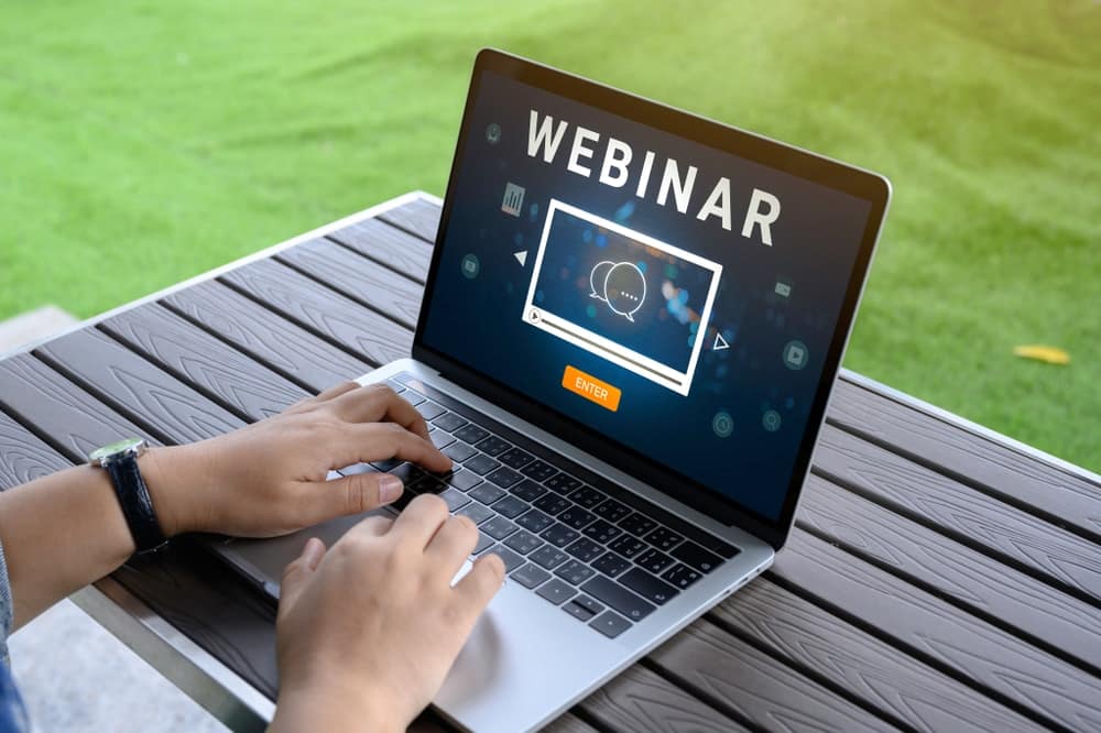 A person participating in a webinar about Texas Legislation while using their laptop with the word webinar displayed prominently.