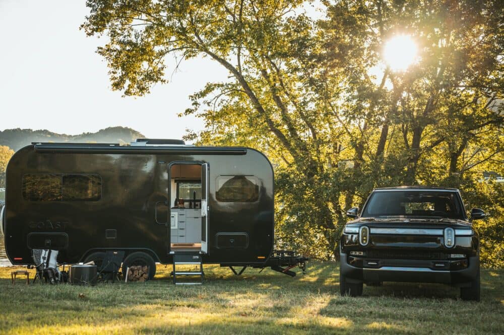 A black truck parked next to a Luxury Off-Grid Travel trailer.