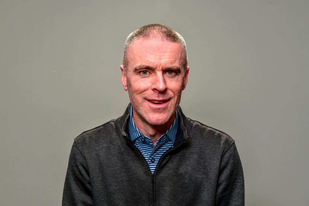Anthony Roberts, in a gray shirt, is smiling.