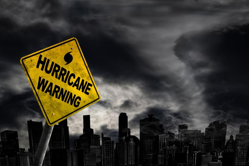 A yellow sign with the words "hurricane warning" in front of a city in Texas.