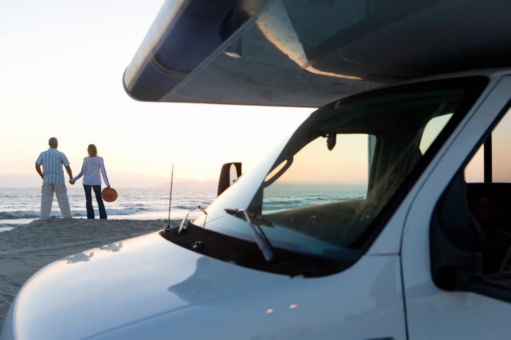 Description: Two industry experts standing next to a white RV on the beach.