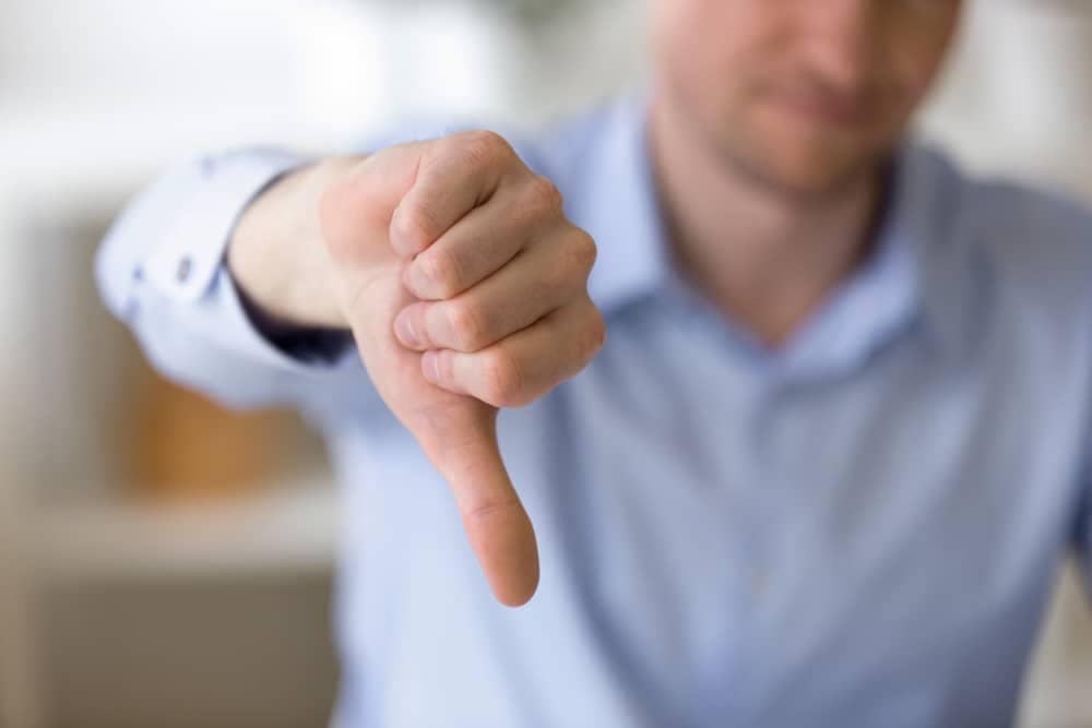 A man is giving a thumbs down sign to express his disapproval.
