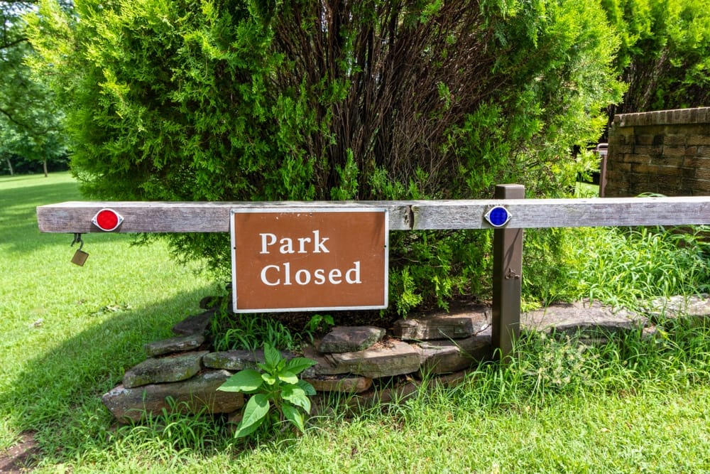 A wooden fence with a sign that says park closed.