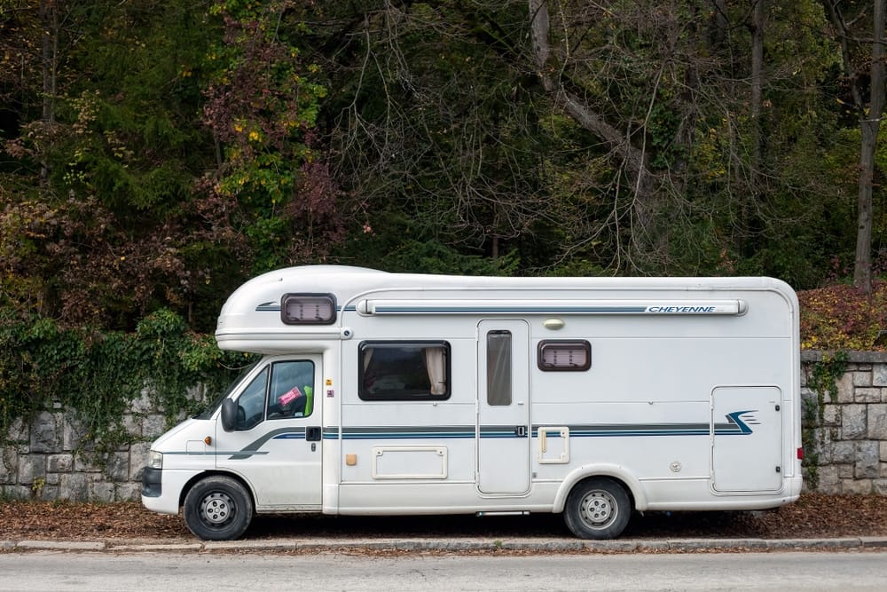 A white RV parked in front of a stone wall in an Ontario Municipality