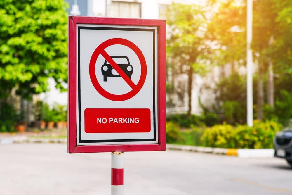 A no parking sign in front of a car, indicating the implementation of an RV parking ban.