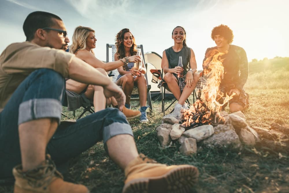 A group of friends sitting around a campfire, enjoying the outdoors.