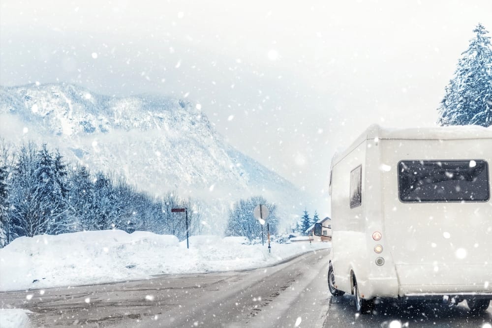 A CanaDream RV is driving down a snowy road, making for the perfect winter road trip.