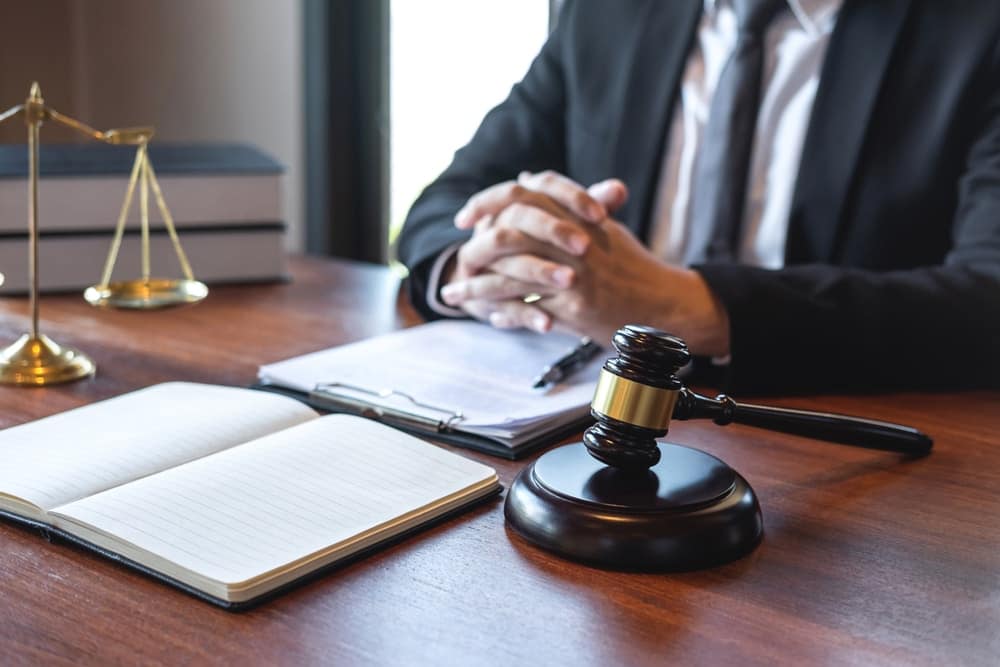 A man in a suit sitting at a desk, participating in the Super Lawyers Panel at the RVDA Expo, discussing strategies for Protecting RV Dealerships.