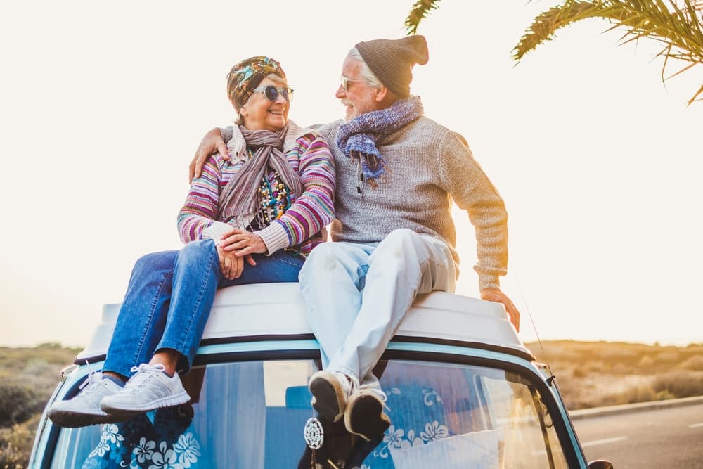 Elderly snowbirds sitting on top of a van at sunset.