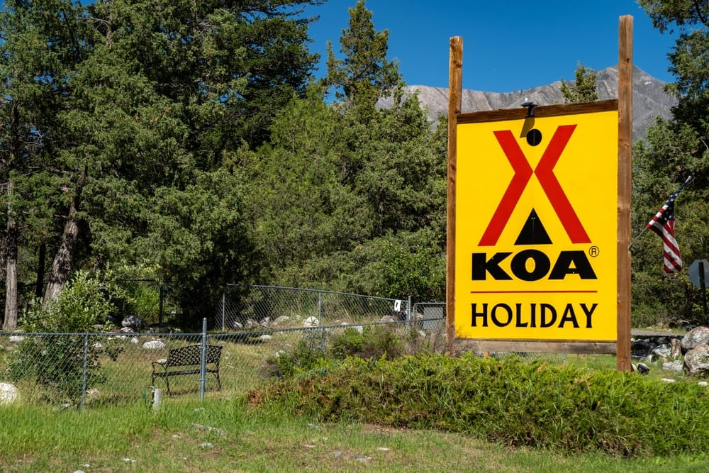 A dedicated position for KOA Canadian market expansion sign in front of a forest.