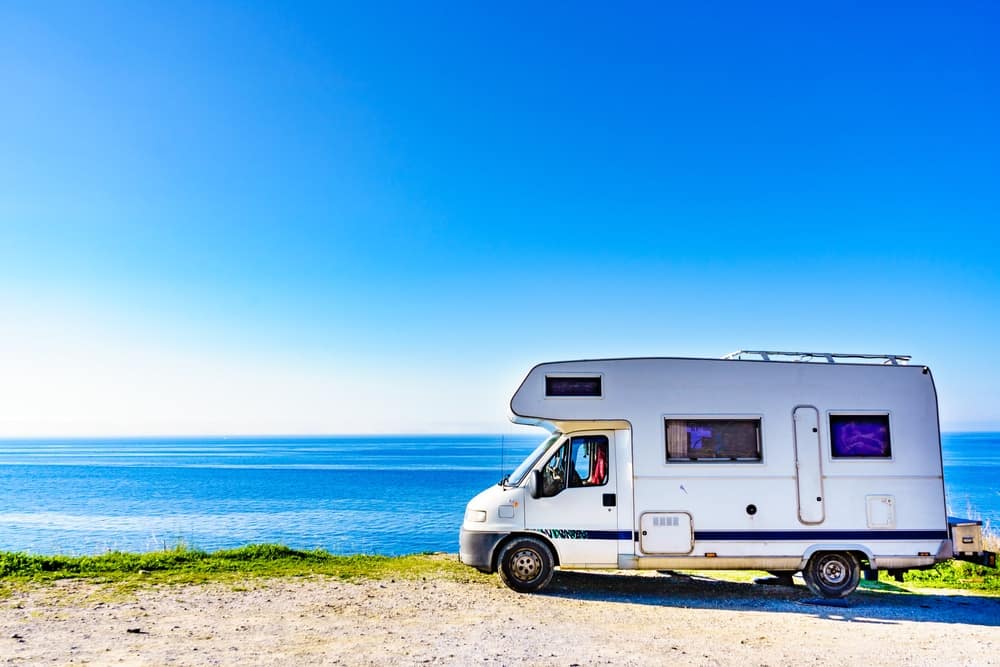 An aftermarket rv parked on a hill near the ocean.