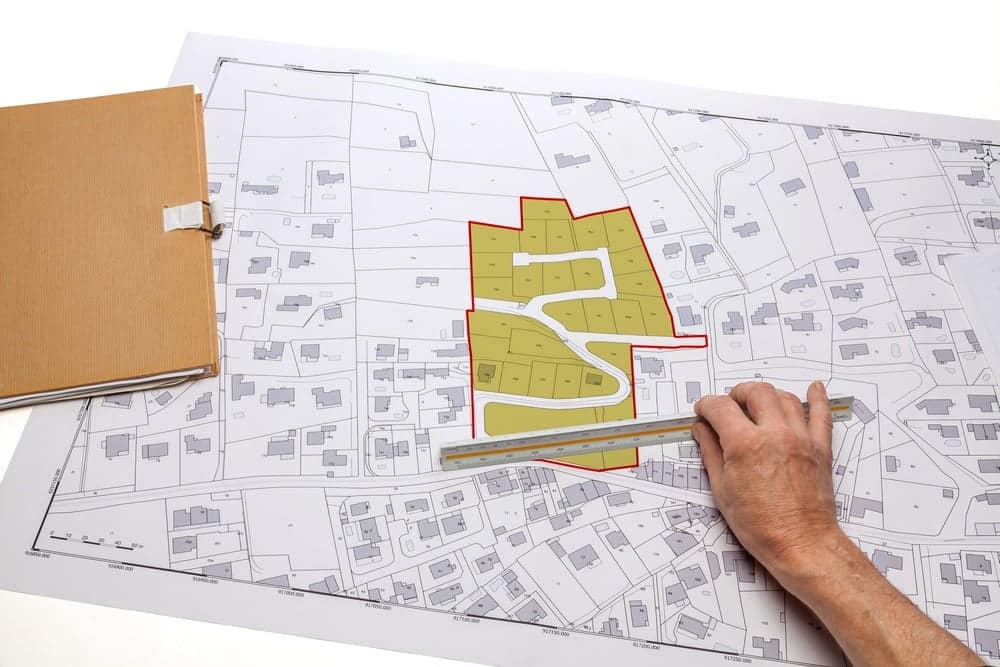 A hand holding a map on top of a folder in a courtroom as part of the Complaint process.