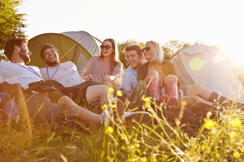 A group of Outdoor-Lovers sitting in the grass near tents at a West Virginia campground.
