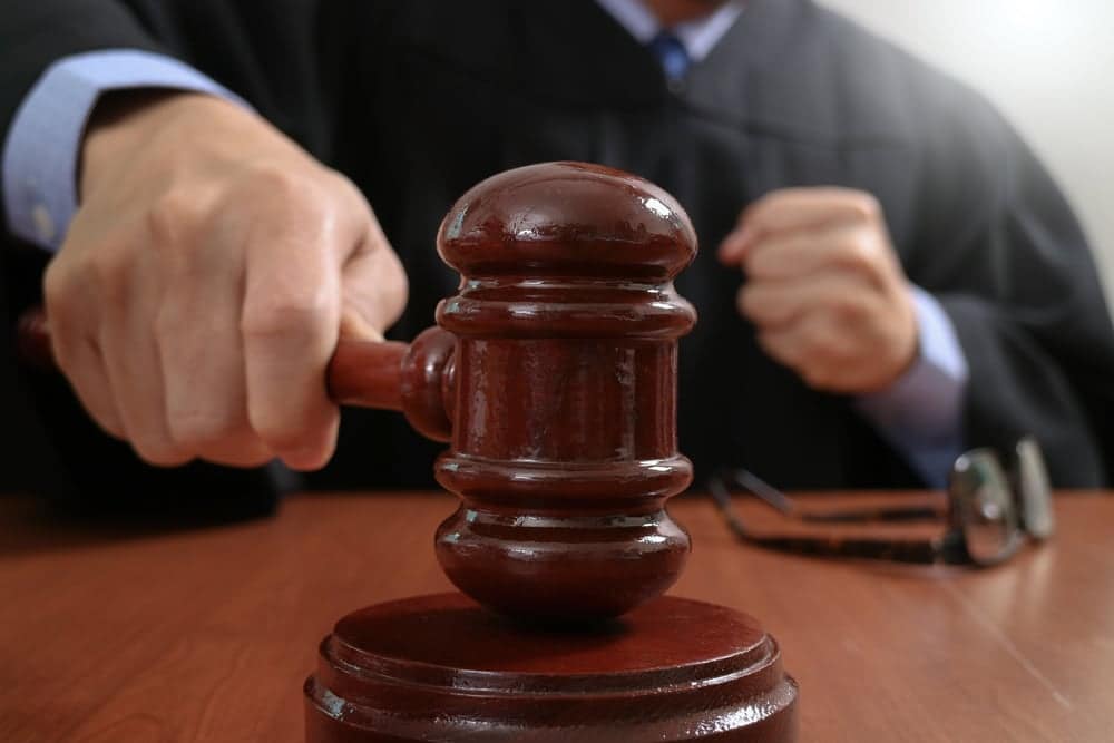 A judge is solemnly holding a gavel on a wooden table while considering a Motion To Dismiss in regards to a Civil Complaint.