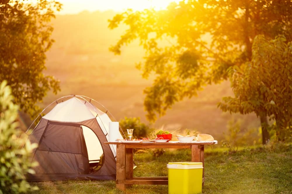A Dream Family Camping Trip under the sunset sky, with a tent set up in a field at Yogi Bear's Jellystone Park.