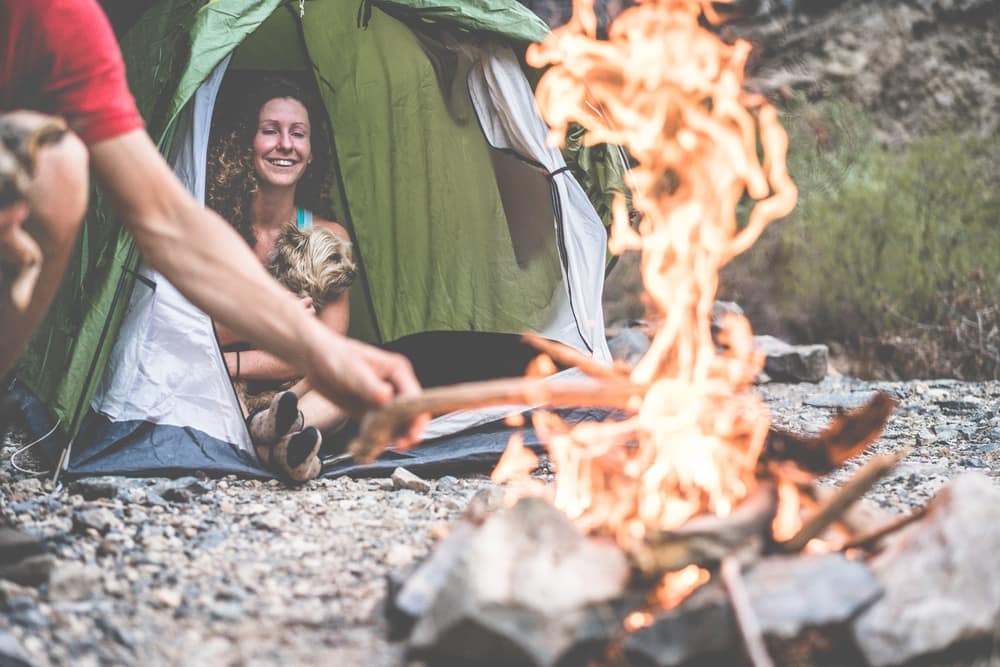 A man and woman sitting next to a campfire in a tent, enjoying the natural beauty of Nevada or California during their conservation project.