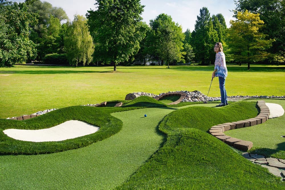 AGS introduces a woman to the putting course game, allowing her to play miniature golf in a park.