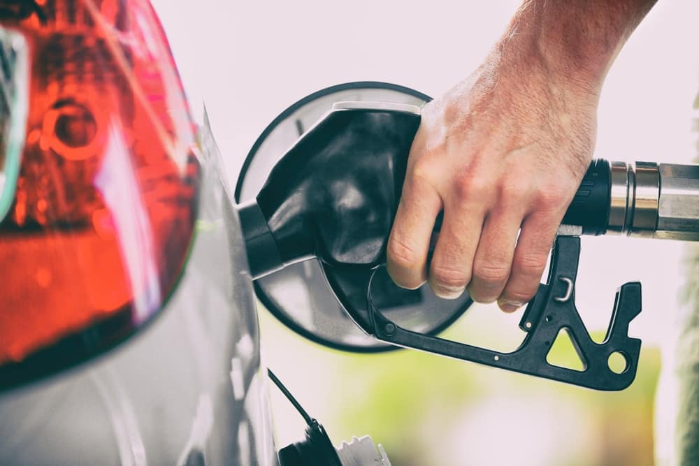A person filling up a car during the holidays, burdened by high gas prices.