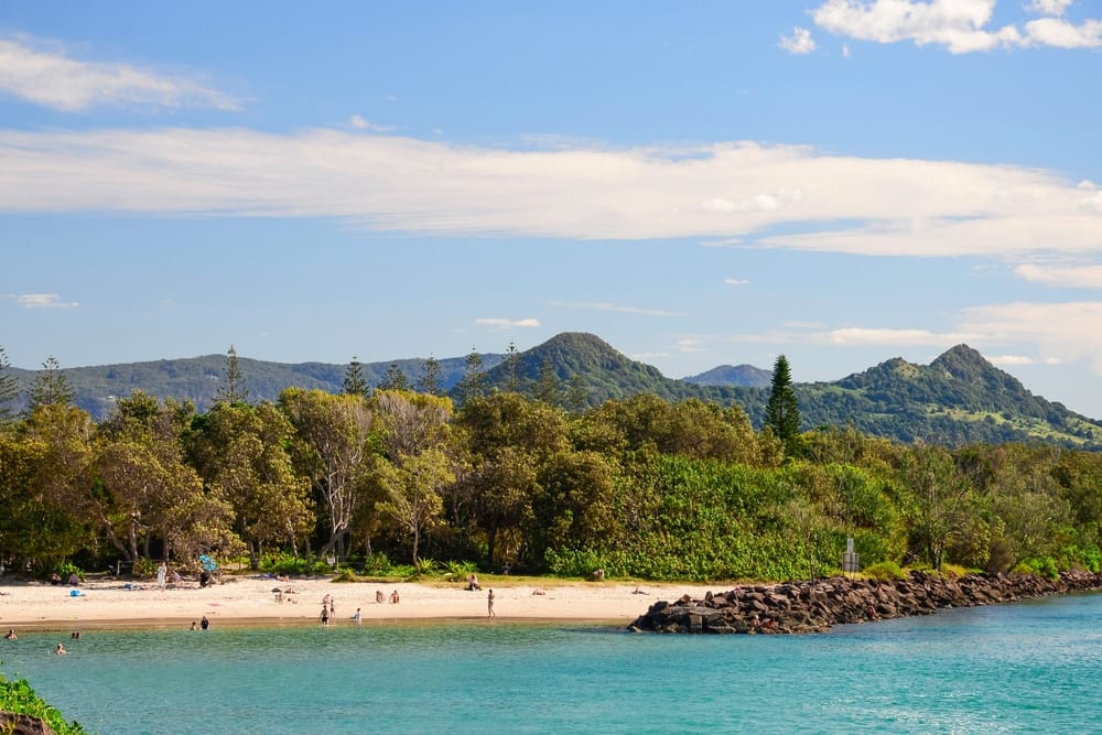 Brunswick Heads Park, a beach retreat with trees and mountains in the background.