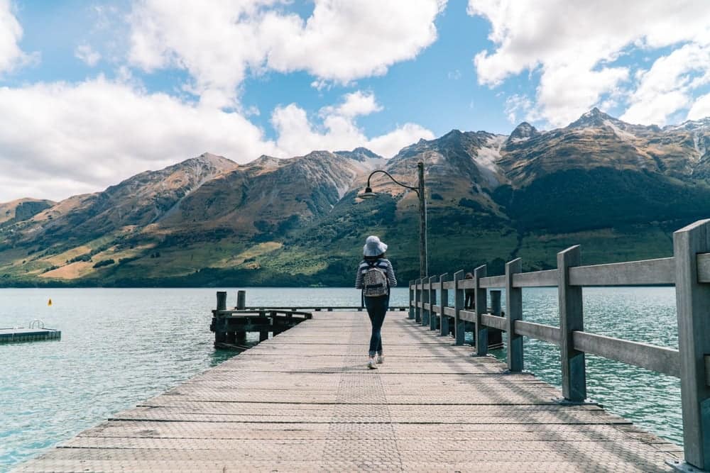 A woman walking on a dock near a lake in New Zealand, at the Zero Net Energy Campground.