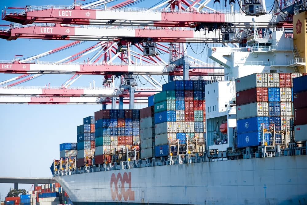 A massive container ship docked at a bustling dock, contributing to the efficient supply chain.