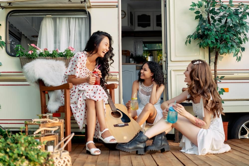 Three women sitting on the porch of an RVshare.