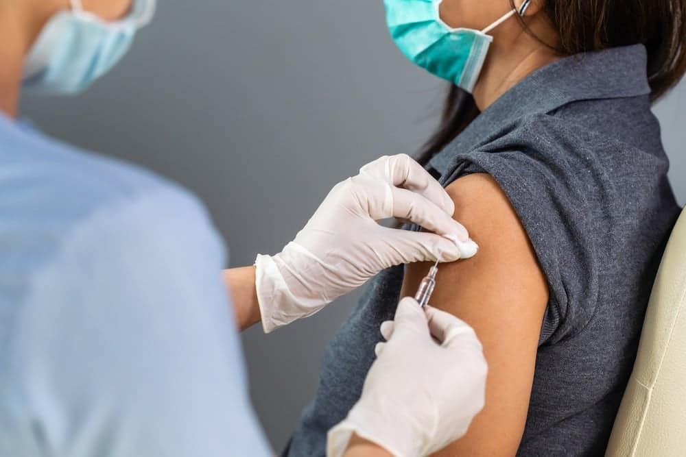 A woman receiving a vaccination in a doctor's office.