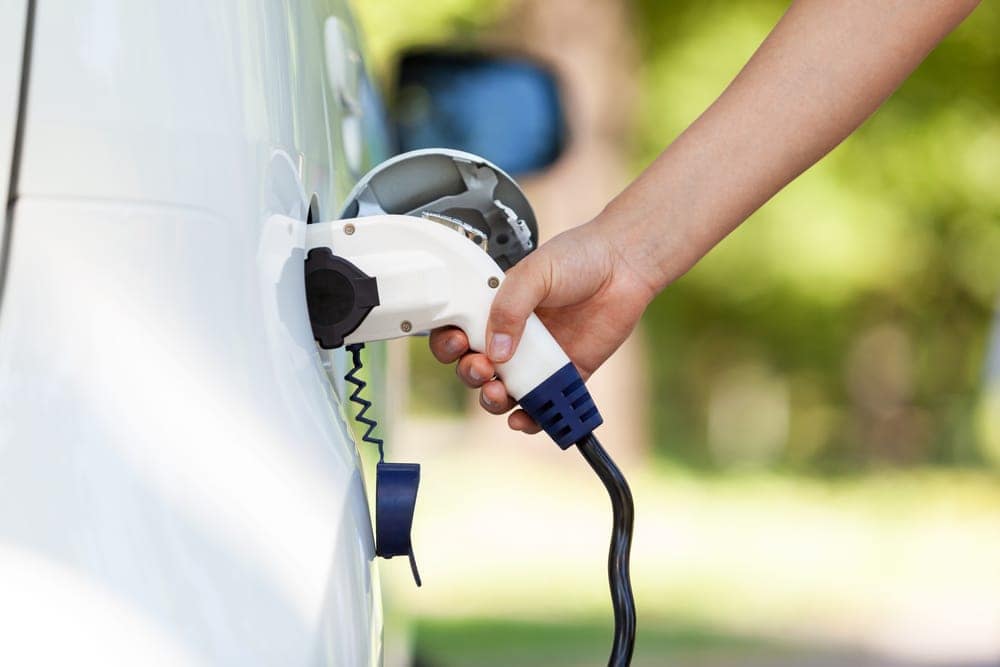 A person plugging an electric car into a KOA camper-friendly EV charging station.