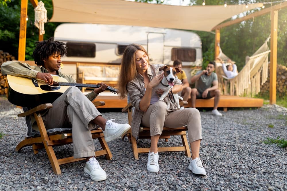 A group of people playing guitar in front of an RV at a Camping World gathering.