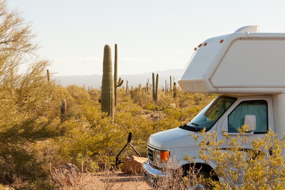 An RV parked in the desert near cactus, showcasing the increased economic impact of the RV industry according to government data.