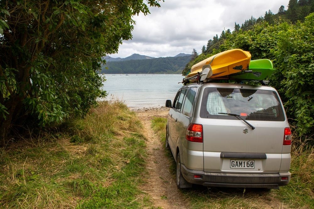 A van parked on a dirt road next to a body of water in the Marlborough District Council area.