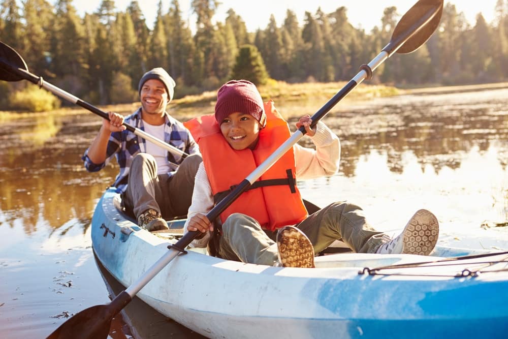 Enactment: Two people enacting a kayak paddle in a serene lake setting.