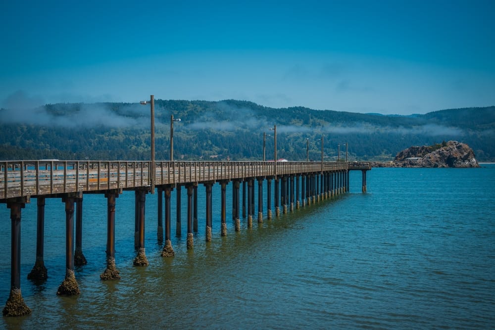A wooden pier extending over the water with mountains in the background at Green Light.