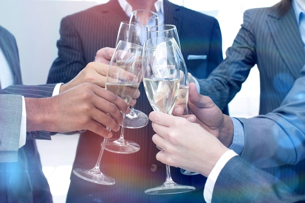 RVReviews.net celebrates 20 years with a group of business people toasting champagne glasses.
