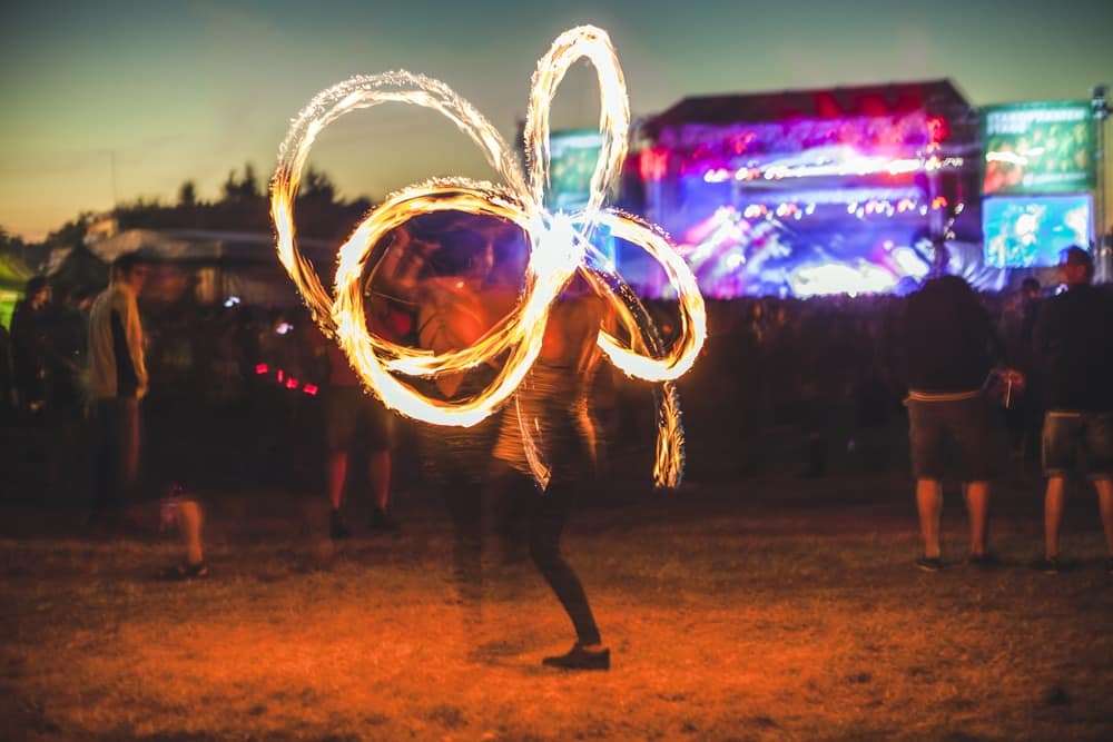 A person spinning a fire wand at a music festival during the 40th Anniversary celebration.