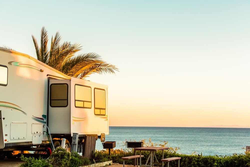 An rv parked on the beach at sunset, offering a perfect post-Covid recreational travel option for consumers.