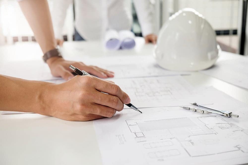 A person is drawing on a blueprint for Genesis Products.