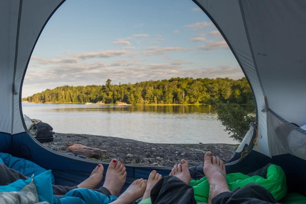 People's feet enjoying a staycation in a tent near a lake in Ontario.