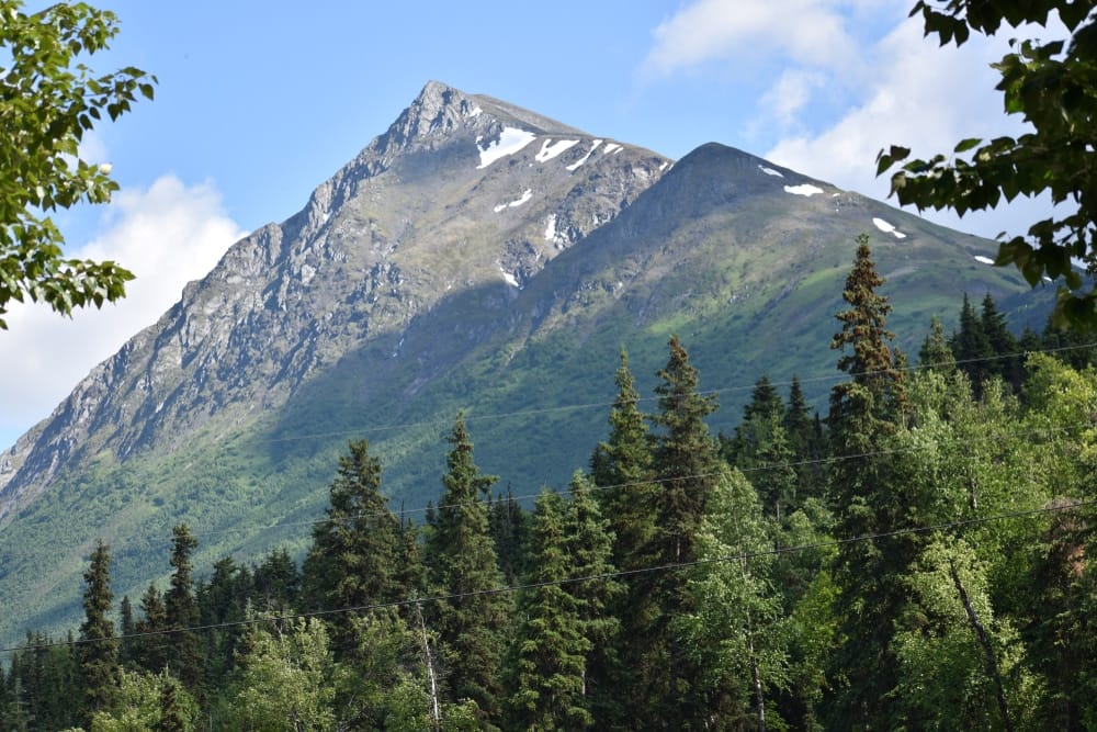 Soldotna, a mountain surrounded by trees and a blue sky, attracts visitors to its scenic campgrounds.