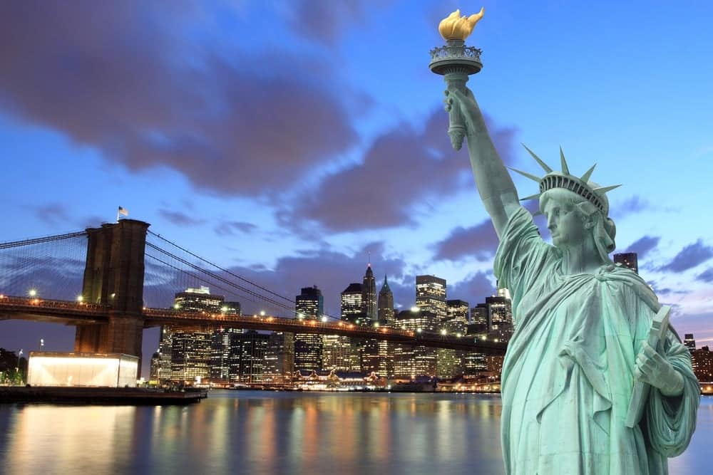 The statue of liberty in new york city at dusk is a popular travel destination, especially during holidays.